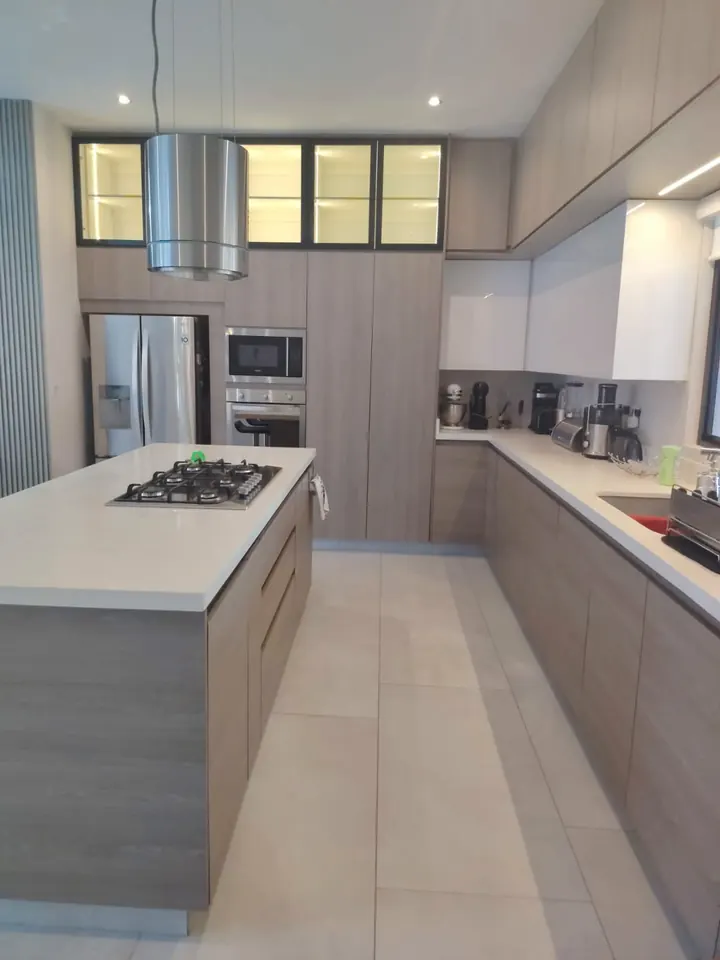Obra real: cocina amplia con isla, parrilla integrada y gabinetes hasta el techo